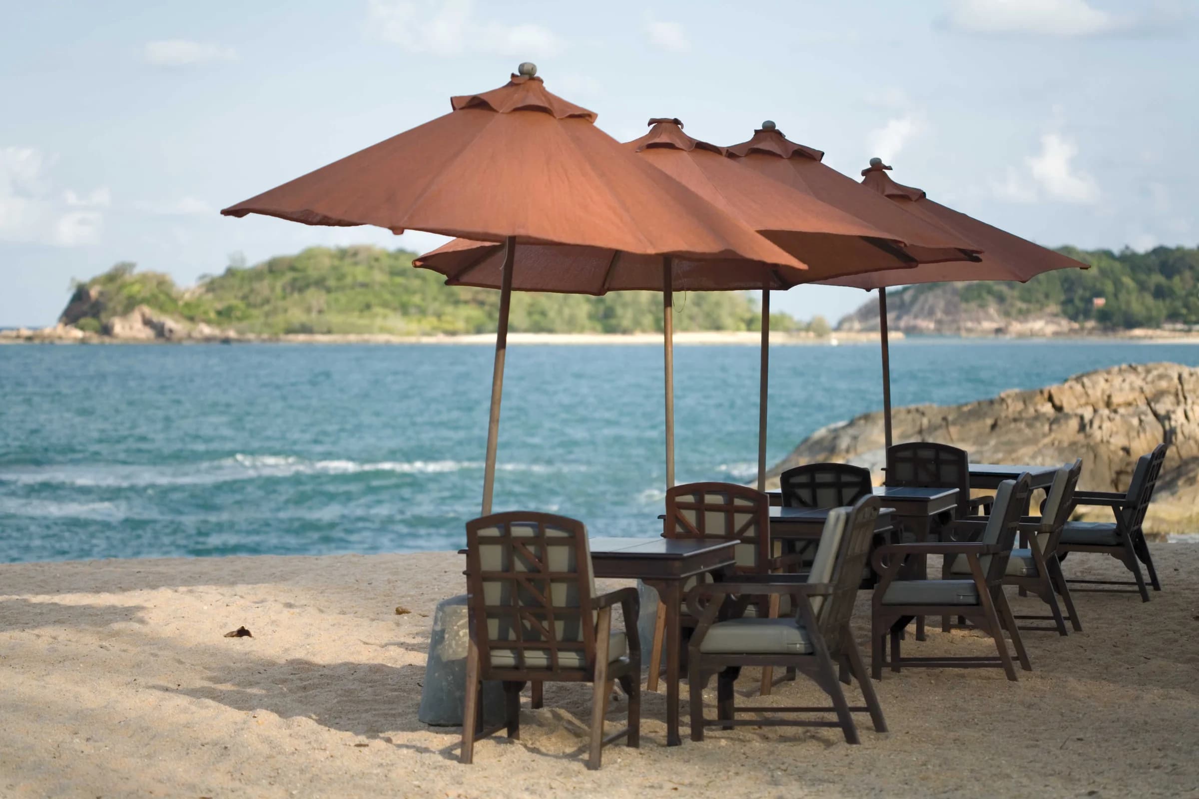 Terracotta parasols shading tables beside the sea on Koh Samui