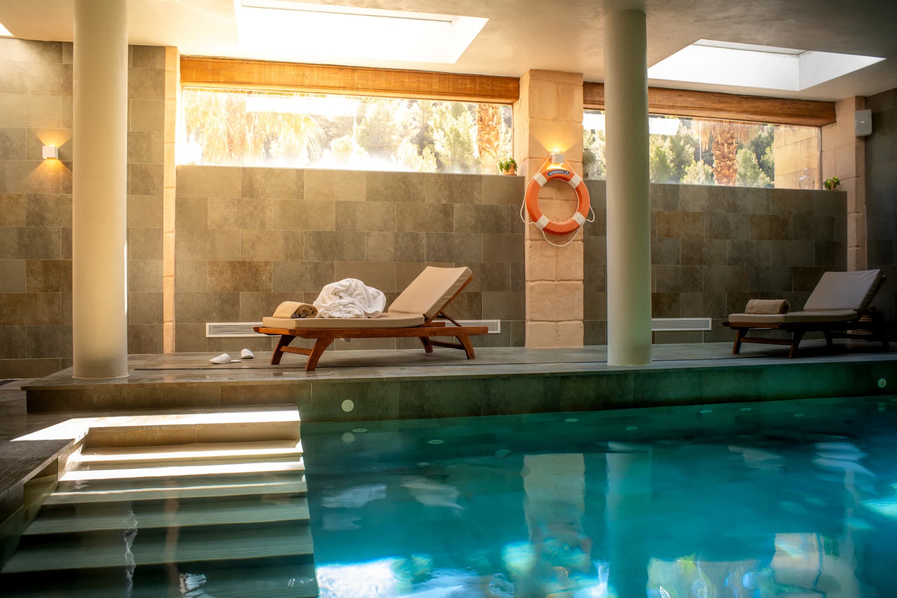 Quiet hotel pool framed by pale stone and blue sky